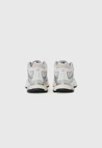 Grå og hvite løpesko med mesh-overdel, polstret krage og reflekterende detaljer, med en dempet såle og slitesterk yttersåle.