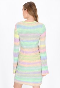 Ribbitutöngd klänning med pastellrand i grönt, rosa, gult och blått. Långa ärmar och en åtsittande silhuett. Mjukt, texturerat tyg.
