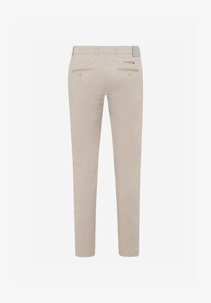 Beige op maat gemaakte broek met riemlussen en twee achterzakken met knopen, achteraan getoond tegen een witte achtergrond.