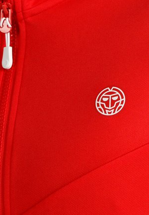 Tissu rouge vif avec une fermeture éclair blanche et un petit logo de visage stylisé blanc imprimé sur le côté droit.