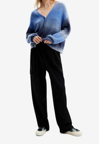 Blå gradient virkad cardigan med V-hals, oversized passform och svarta vida byxor. Vita sneakers med blommönster.