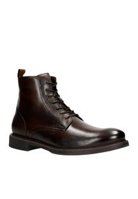 Bruine leren enkelboot met een ronde neus, vetersluiting, verhoogde stiksels en een contrasterende tan trekstrip op de hiel.