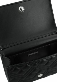 Borsa a tracolla in pelle nera trapuntata con una texture liscia; presenta una chiusura a pulsante e un'etichetta interna che recita "LOVE MOSCHINO."