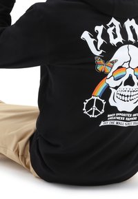 Sudadera negra con capucha y un diseño gráfico que incluye una calavera, una mariposa, un arcoíris y un símbolo de la paz. Confeccionada en tela suave, de corte relajado y con bolsillo frontal.
