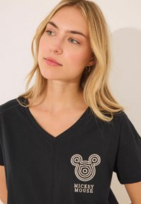 Zwarte V-hals T-shirt met een gestructureerd, geborduurd Mickey Mouse ontwerp in beige op de linkerborst en korte mouwen.
