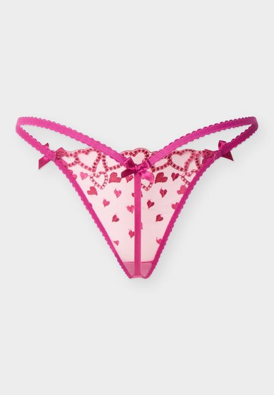 Tanga rose transparent avec des cœurs brodés, des bords festonnés et de petits nœuds en satin sur les côtés et au centre devant.