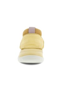 Chaussure beige à enfiler avec une large sangle texturée, un col en mesh et une semelle blanche, vue de face sur un fond blanc.
