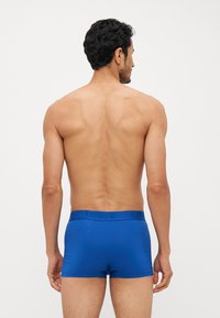 Boxer shorts de algodão azuis com um ajuste justo, apresentando uma cintura elástica com o logo da marca em relevo, vistos pela parte de trás.