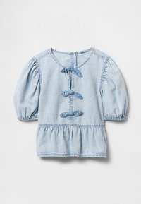 Lys blå denimbluse med puffede halvlange ermer, tre knuter i stoff foran, og rynket peplumkant på hvit bakgrunn.