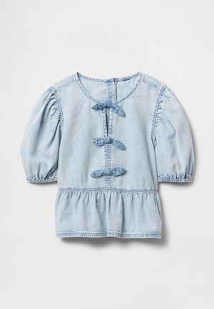 Világoskék farmer blúz puffadt fél ujjakkal, három elől vászonból készült megkötő csomóval és redőzött peplum szegéllyel, fehér háttéren.