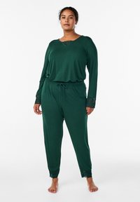 Zelena sproščena obleka z dolgimi rokavi in čipkastim robom na izrezu in rokavih, kombinirana z hlačami z elastičnim pasom. Gladek teksturni material.