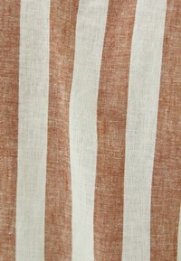 Linneväv som har växlande ränder i rost-röd och vit. Texturen är något grov med ett naturligt vävmönster.