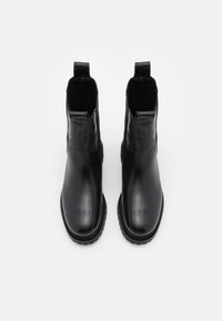 Paire de bottines Chelsea en cuir noir avec bouts arrondis et languettes, vues de dessus sur fond blanc.