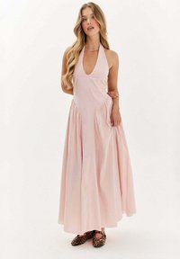 Ružová šaty s halter strihom a hlbokým V-výstrihom, s plisovanými stranami a splývavou sukňou, v kombinácii s balerínami s leopardím vzorom. Hladká tkanina a minimalistický dizajn.