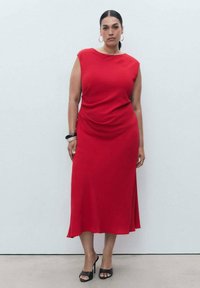Rotes ärmelloses Kleid mit drapiertem Design, knielangem Saum und seitlichem Schlitz. Der glatte Stoff und die minimalistische Silhouette betonen die allgemeine Eleganz.