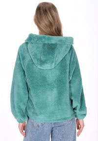 Türkiser Fleece-Hoodie mit weicher, plüschiger Textur, oversized Passform und Kapuze. Verfügt über leicht geraffte Ärmel und einen abgerundeten Saum.