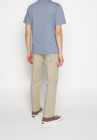 Light blue short-sleeve t-shirt paired with beige cargo pants. The pants have visible pockets and are worn with brown sneakers.