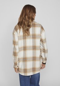 Flanelová košile v krémové, béžové a šedé kostce; oversized střih s dlouhými rukávy; zapínání na knoflíky na manžetách; měkká, texturovaná tkanina.