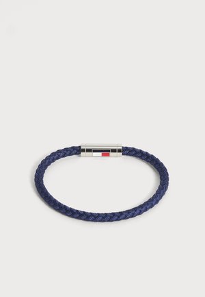Bracelet tressé bleu marine avec un fermoir magnétique argenté présentant un petit motif rectangulaire rouge, blanc et noir.