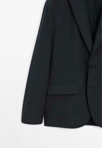 Blazer scuro realizzato in tessuto morbido, con rever a punta, chiusura a un bottone e tasca laterale. Linee pulite e design aderente.