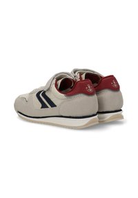Zapatillas de ante beige con una sobrecubierta de cuero blanco, rayas en azul marino, acentos rojos en el talón y una suela texturizada.