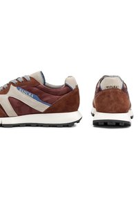 Hnedé a sivé semišové tenisky s bielou stredovou podrážkou, doplnené modrými akcentmi a logom. Dizajn obsahuje textúrovaný vzor a gumovú podrážku.