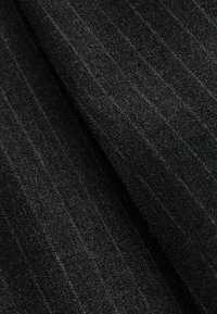 Tissu gris foncé avec un motif subtil de fines rayures verticales, légèrement plié pour montrer la texture et les détails du tissage.