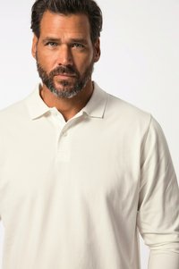 Hvid langærmet polo shirt lavet af glat stof. Den har en klassisk krave, knaplukning og en afslappet pasform uden synlige mønstre.