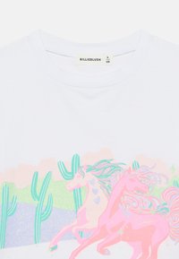 Λευκό βαμβακερό μπλουζάκι με πολύχρωμο σχέδιο δύο μονόκερων με γκλίτερ, κάκτους και παστέλ σύννεφα στο φόντο.