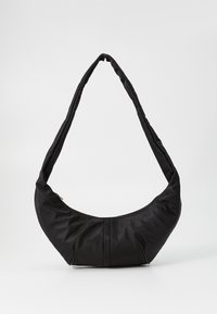 Borsa a spalla nera realizzata in nylon morbido con un design curvo e imbottito. Presenta una chiusura con zip e una tracolla allungata e flessibile. Stile minimalista.