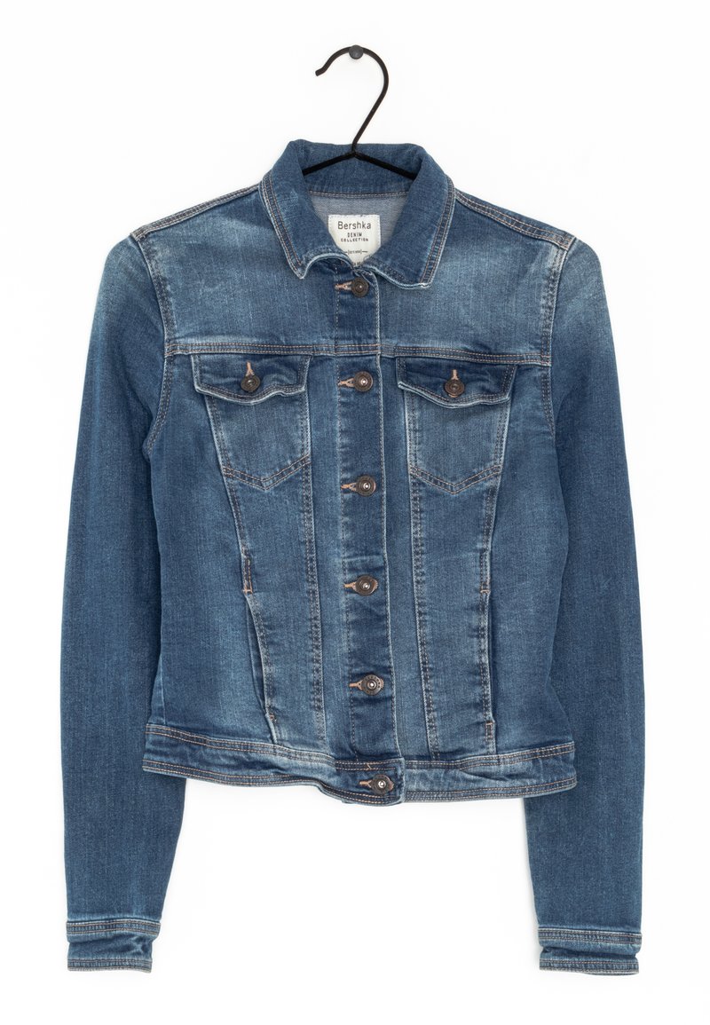 Modrá džínová bunda s klasickým designem, zapínání na knoflíky, dvě přední kapsy a dlouhé rukávy. Má mírné vyblednutí a hnědé knoflíky.