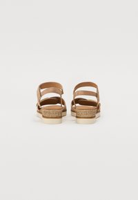 Brown leather sandals with multiple straps, featuring a woven jute midsole and a white rubber outsole. Rear view, minimalistic design.