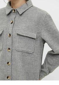 Graues Hemd aus Wollmischung mit Knopfleiste, einem Kragen, zwei aufgesetzten Taschen vorne und großen braunen Knöpfen entlang der Blende.