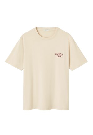 T-shirt en coton couleur crème à manches courtes, coupe décontractée, avec un petit texte graphique bordeaux sur le côté gauche de la poitrine.