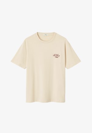 T-shirt en coton couleur crème à manches courtes, coupe décontractée, avec un petit texte graphique bordeaux sur le côté gauche de la poitrine.