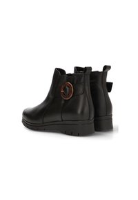 Botas de tobillo de cuero negro con puntera redondeada, detalle circular marrón y tacón bajo. Textura suave y un diseño minimalista en la superficie.