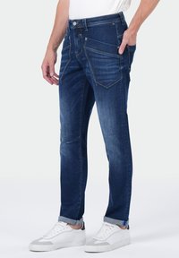 Donkerblauwe denim jeans met een slim fit, met meerdere voorkwasten, contrasterende stiksels en een opgerolde zoom.