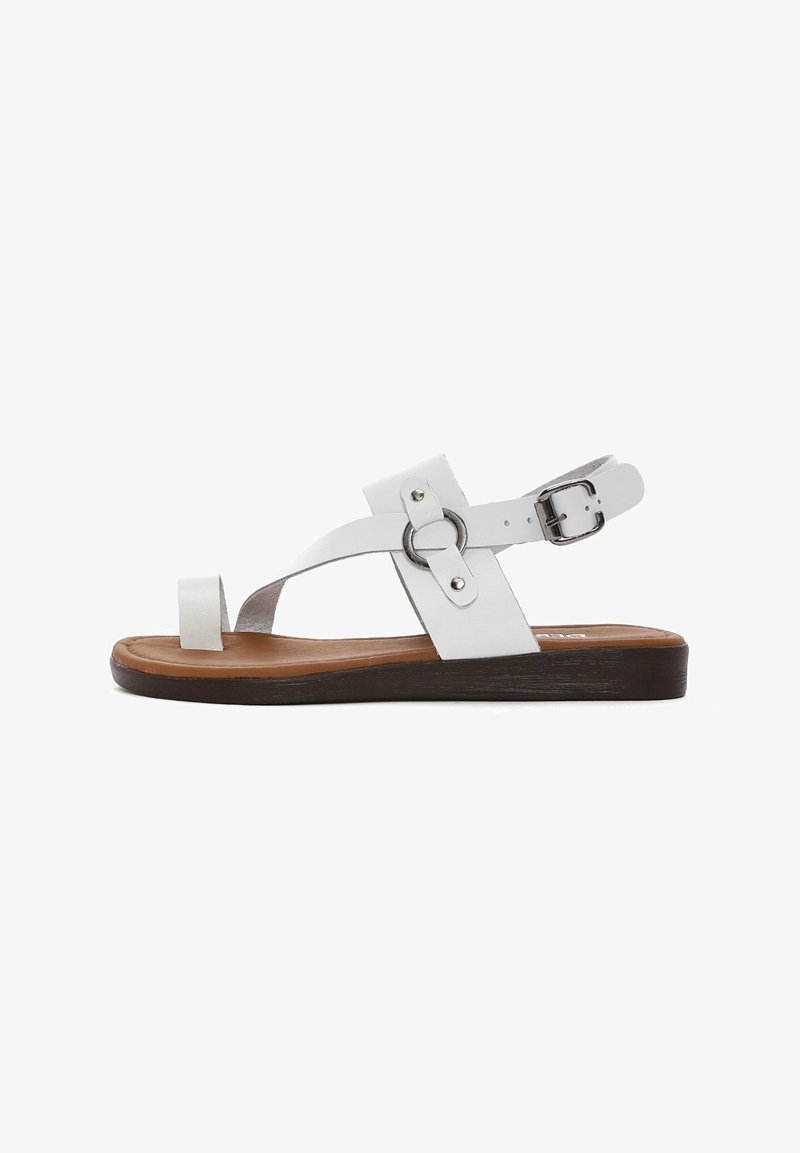 Sandal in pelle bianca con punta tonda e suola in gomma marrone, dotata di cinturino alla caviglia regolabile. Presenta un accent metallico circolare e una texture liscia.