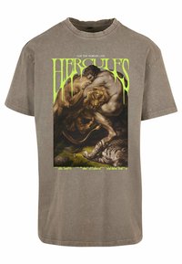 Grafisk T-skjorte i grått stoff. Har tekst i livlig grønt som sier "Herkules" og en illustrasjon av Herkules som kjemper mot en løve. Korte ermer, rund hals.