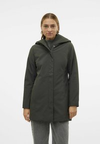 Chaqueta verde impermeable con capucha, cremallera frontal, bolsillos laterales y un forro interior texturizado, que presenta un corte recto y un diseño minimalista.