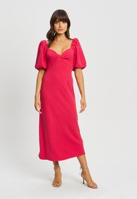 Abito midi fucsia con maniche a sbuffo e scollatura a cuore. Tessuto morbido con busto aderente, gonna fluida e un delicato dettaglio a fiocco.