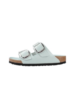 Sandali slide azzurro chiaro con due fibbie argentate regolabili, plantare in sughero e suola in gomma nera. Finitura liscia e design minimalista.