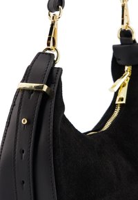 Schwarze Wildleder-Schultertasche mit einem glatten Ledergriff, goldfarbenen Hardware-Akzenten und einem Reißverschluss. Strukturierte Oberfläche mit Stickdetails.