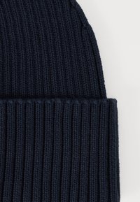 Gorra de punto azul marino con textura acanalada y puño doblado. Fabricada con material suave, presenta líneas verticales en toda su superficie.