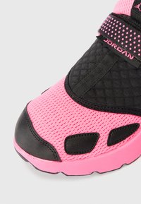Pantofii sport negri și roz au un superior din plasă, textură capitonată și curea ajustabilă. Au decupaje notabile și o talpă groasă.