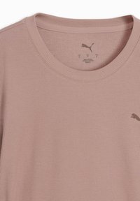 Ανοιχτό μοβ ριμπ πλεκτό μπλουζάκι με στρογγυλή λαιμόκοψη και μικρό λογότυπο Puma στο επάνω μέρος του στήθους, χωρίς ετικέτα και με εκτυπωμένη ετικέτα στο εσωτερικό του γιακα.