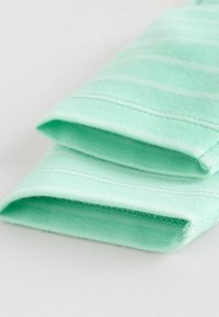 Foldet lysegrønt stof med subtile horisontale hvide striber, der viser detaljeret syning på kanterne.