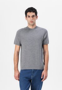 Γκρι κοντομάνικο πουλόβερ με κυκλικό λαιμό, φτιαγμένο από μαλακό και ελαφρύ υλικό. Διαθέτει ελάχιστες ραφές και ίσια γραμμή.