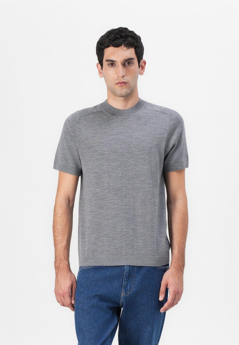 Γκρι κοντομάνικο πουλόβερ με κυκλικό λαιμό, φτιαγμένο από μαλακό και ελαφρύ υλικό. Διαθέτει ελάχιστες ραφές και ίσια γραμμή.