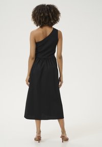 Svart, axelbandslös klänning med en figursydd överdel och elastisk midja, med en flödande kjol som når mitt på vaden. Slät textur.